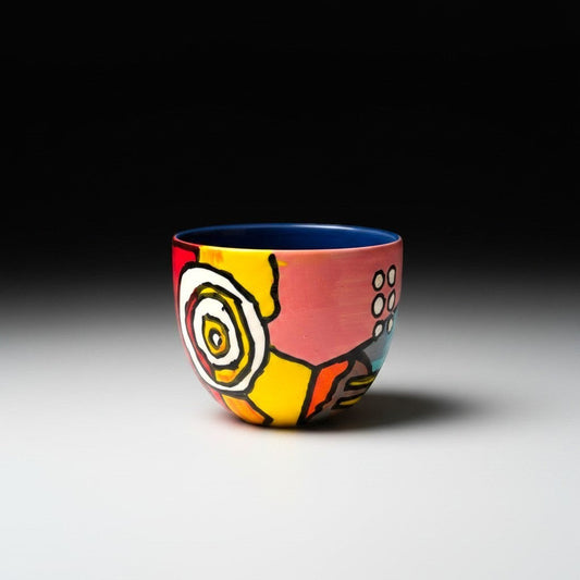 CeramicMeltdown.com abstract art wine cup with pink, yellow, red, and blue glaze. Features a spiral design and dotted pattern.
