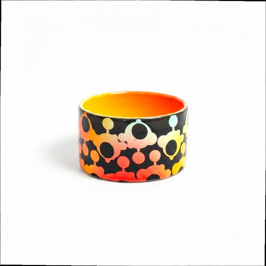 CeramicMeltdown.com small catch-all dish with a black exterior featuring a gradient bubble pattern in orange, yellow, and light blue. Bright orange interior.