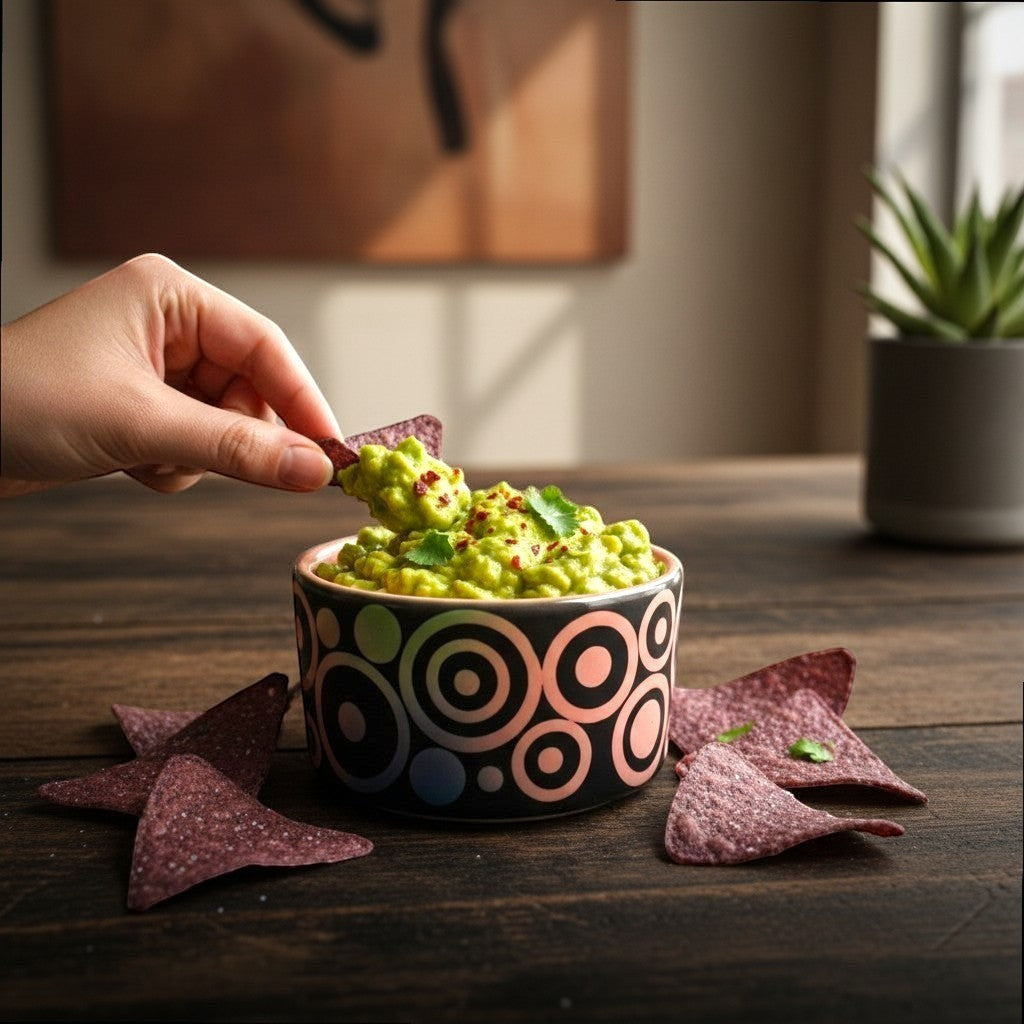 CeramicMeltdown.com black ceramic trinket dish with rainbow concentric circles and coral interior, holding guacamole.