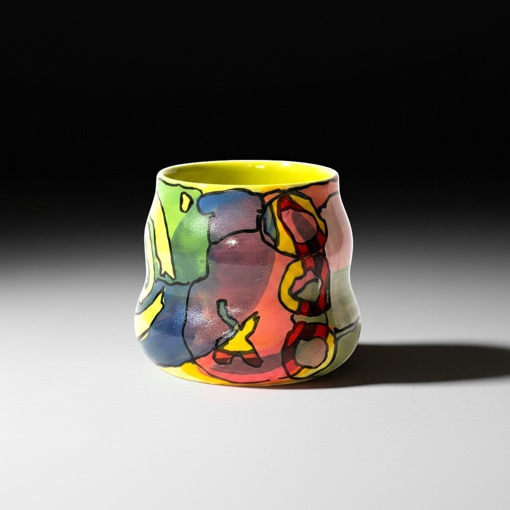 CeramicMeltdown.com abstract art cocktail cup with yellow interior and colorful exterior featuring bold black outlines.