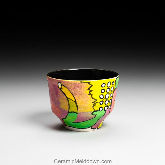 CeramicMeltdown.com hand-painted ceramic cup with abstract colorful design in yellow, pink, green, and purple. Features textured surface and black interior.