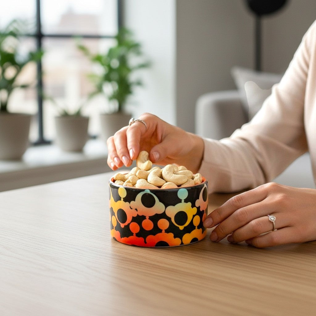 CeramicMeltdown.com small black catch-all dish with colorful bubble pattern, holding cashews.