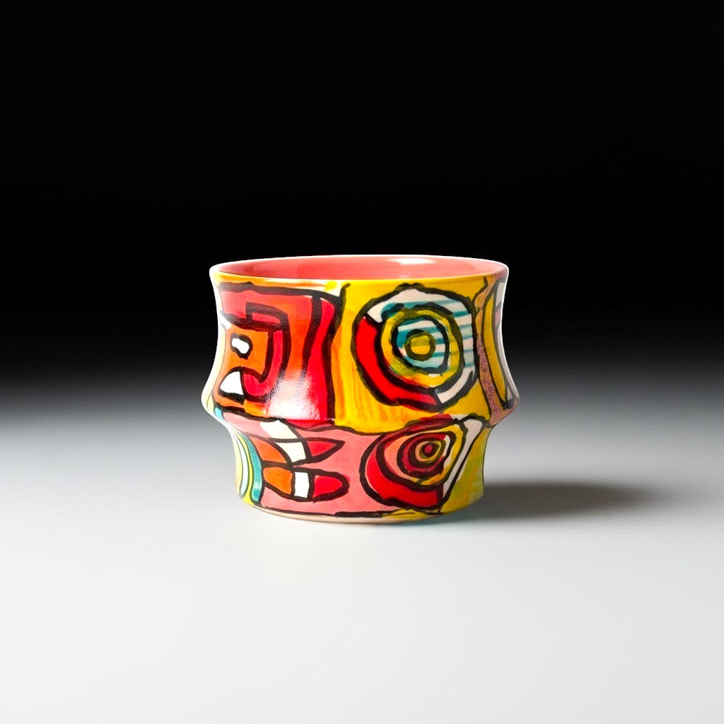 CeramicMeltdown.com Freedom Cup, a vibrant ceramic mug with a coral interior and a colorful abstract swirl design in yellow, red, pink, and blue.