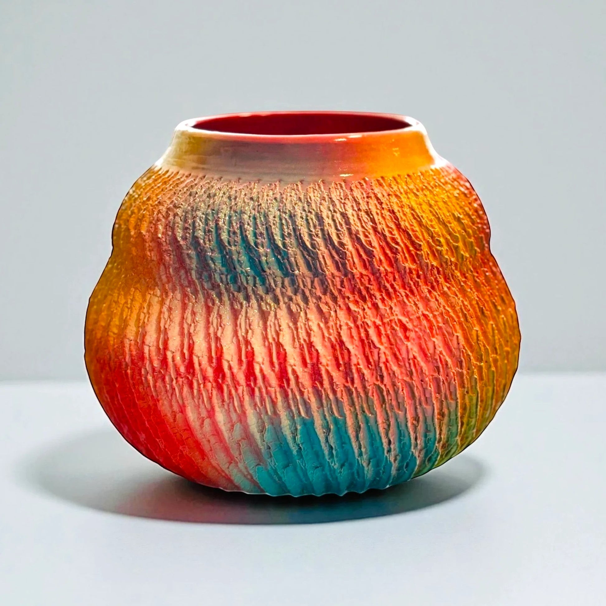 CeramicMeltdown.com textured ceramic vessel with abstract swirl pattern in red, orange, yellow, blue, and green hues.