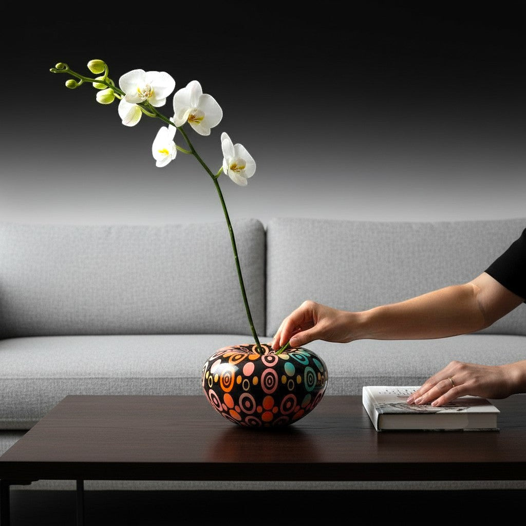 CeramicMeltdown.com oval vase with colorful concentric circles pattern on black background, holding white orchid.