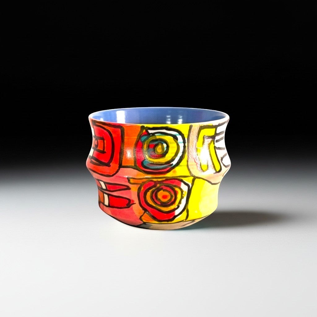 CeramicMeltdown.com hand-painted abstract ceramic mug in red, yellow, and blue with a blue interior.