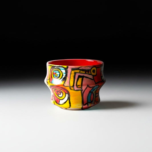 CeramicMeltdown.com Freedom Cup, a vibrant, abstractly painted ceramic vessel with a red interior and a unique, undulating shape.